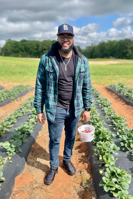 A man standing in a vegetable field in black watch winter sherpa lined flannel shirt jacket for men