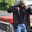 Men in men's brown flannel lined shirt jacket leaning against car