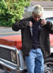 Men in men's brown flannel lined shirt jacket leaning against car