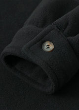 Close-up of the cuff of solid black white men's sherpa lined shirt jacket with button closure