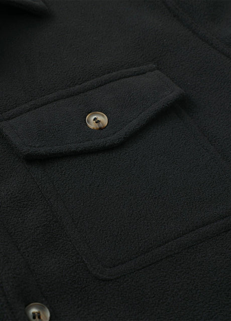 Close-up of the pocket of solid black men's winter button closure shirt jacket