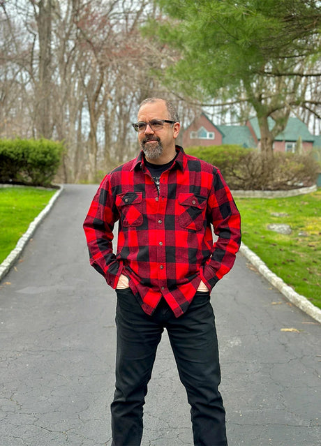 A man stand in the street in a red buffalo plaid heavyweight flannel plaid shirt