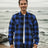 A man standing on the beach in a buffalo blue men's fleece lined flannel shirt jacket 