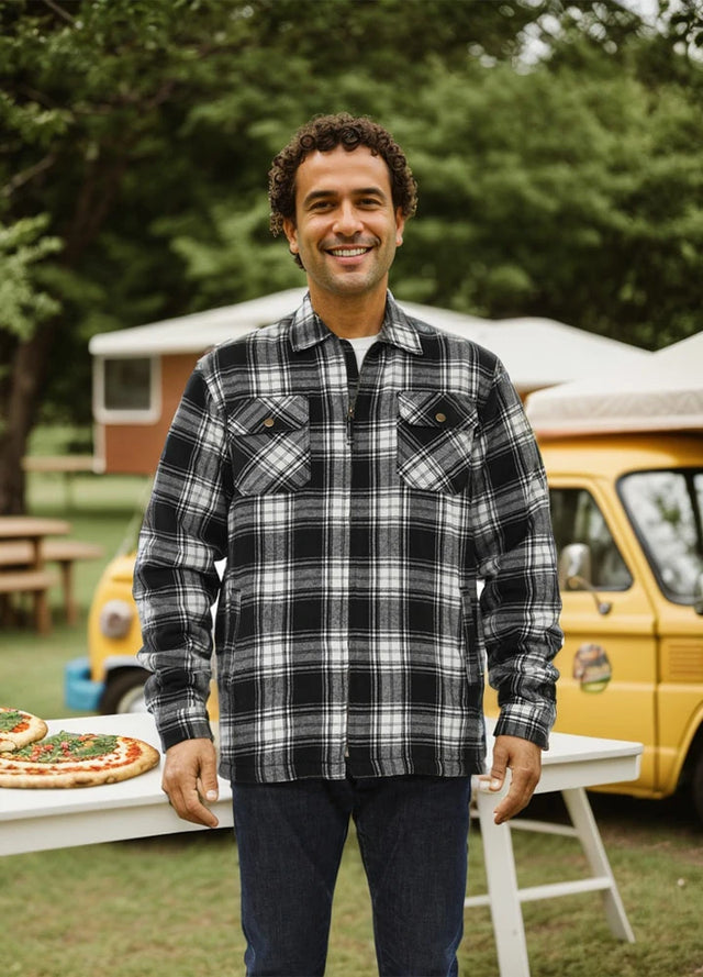 A man stands in front of the table in a black white men's fleece lined flannel plaid shirt jacket